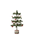 The Maileg Christmas Tree by Maileg features sparse green branches, red ornaments, white candles, and mushrooms in a round base with a red and white diamond pattern—perfect for festive charm next to a Gingerbread House.