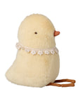 The Maileg Chicken Plush, Small features fluffy yellow fur, a lace flower collar, and a brown string. Soft to the touch with black eyes and an orange beak. Shown on a white background.
