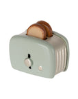 The Maileg Toaster by Maileg is a small, pale green metal toaster with two slices of toast inside, featuring a button and dial design—perfect for any Mouse Hole Farmhouse playset.