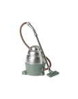 The Maileg Vacuum Cleaner by Maileg features a vintage silver metal body, green base, braided hose, and a green rectangular floor nozzle—ideal for effortless cleaning. Shown against a plain white background.