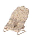 The Maileg My Babysitter by Maileg is a small doll chair with a scalloped backrest, light beige fabric featuring a pink and yellow floral pattern, and a simple metal base.