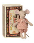 A Maileg Big Sister Mouse doll in a pink polka-dot outfit stands before a vintage-style "Matchbox" toy, set among colorful text and charming illustrations.