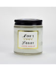 The Austin Press Travel Candle by Faire features botanical waxes in a clear glass jar with a black lid, labeled “Monk’s Library” in decorative font, and is photographed against a plain white background.