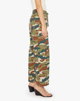 A person wears Mother’s The Drawn Half-Pipe Ankle high-waisted camouflage cotton pants with a drawstring waist, clear strap heels, and a white sleeveless top, shown in profile against a plain background.