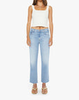 A woman wearing a white sleeveless crop top and gold sandals stands facing forward against a white background, styled in Mother’s The Mid Rise Rambler Zip Ankle Fray jeans.