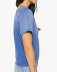 A woman with long dark hair, shown from the side against a white background, wears Mother's The Short Sleeve Concert Tee in blue with rolled sleeves and light blue jeans.