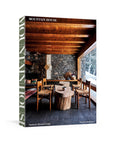 The "Mountain House" book from Random House features a cozy, rustic cover with wooden beams and stone walls, showcasing snowy mountain views and capturing the charm of mountain homes. Author: Nina Freudenberger.
