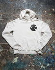 The Made Worn Peace Love Oversized Hoodie, featuring a black circular logo on the left chest, is displayed flat on a colorful, paint-splattered concrete surface—perfect as a winter sweatshirt for Peace Love Art enthusiasts.