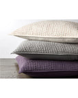 The Coyuchi Inc Pebbled Org Sham Euro Slate, crafted from soft organic cotton with a quilted texture, is shown stacked on a wooden surface against a white background.