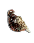 The Faire Hand Painted Pigeon Clip is an eco-friendly cellulose acetate brooch, featuring a simple brown and beige stylized pigeon with a glossy finish and faint gray shadow on a plain white background.