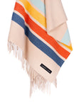 The Sackcloth & Ashes/Camp Coast by Sackcloth & Ashes is a beige wool blanket made from recycled materials, with fringed edges, horizontal stripes in blue, orange, red, and light blue, and a small black label near the bottom.