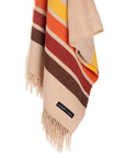 The Sackcloth & Ashes Desert Camp scarf by Sackcloth & Ashes is a cozy beige accessory with brown, orange, red, and yellow horizontal stripes, fringed ends, and a small black label near the fringe.