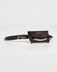 The Rachel Comey Double Wrap Hamcon Belt w/ Pouch is a small, dark brown calfskin belt bag with a flap and gold-tone hardware, shown laid flat on a white surface.