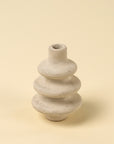 The Ripple Paper Mache Bud Vase by Indaba is a small, light gray handcrafted piece with three stacked ring-like sections and a narrow opening—perfect for sustainable decor in any space.