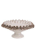Handcrafted by Faire, the Compote with Ruffles is a white ceramic pedestal cake stand featuring a fluted, ruffled edge with light brown trim, reminiscent of classic compotes, shown against a plain background.