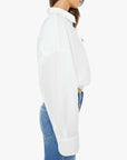 A woman in The Scrunchie Frenchie white cotton top by Mother and blue jeans stands in profile against a plain white background.