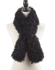 A mannequin showcases the Faire Lamb Fur Pull Through scarf, its fluffy black fur crossed in front for a cozy, stylish look. The plain white background highlights the luxurious warmth and chic texture of this elegant accessory.