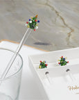 A Be Home Tree Glass Swizzle Stick, featuring a festive Christmas tree topper, sits in a glass beside a white box holding two more from the Tree Glass Swizzle Sticks S/4 set.