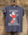 A faded vintage-style Lynyrd Skynyrd Crew Tee by Made Worn, 100% cotton and made in the USA, hangs on a wooden hanger. It features a dog in a cowboy hat with the American flag and "Lynyrd Skynyrd" text.