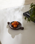 The Accent Decor Brownwood Tray /Small holds small oranges on a white table beside books and a green plant in sunlight, making it perfect for stylish coffee table decor.