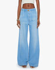 Someone wears The Kitchen Drawer Skimp by Mother—light blue, high-rise wide leg jeans crafted from a recycled cotton blend with an elastic waistband and pockets—paired with a cropped white top, posed against a plain background.