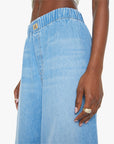 Close-up of a person wearing Mother’s The Kitchen Drawer Skimp light blue wide leg jeans with a high-rise elastic waistband in recycled cotton blend. Gold ring, light pink manicure. Plain white background.