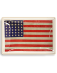 An aged American flag displayed in a glass frame, featuring 13 horizontal stripes and a blue canton with 50 stars, exhibiting a vintage aesthetic in a Scottsdale Arizona bungalow by Ben's Garden Tray 5.5" x 8.5".