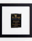 A framed matchbook cover from St. Regis, encased in a clear acrylic frame, advertising an air-conditioned restaurant, cafeteria, and bar with "popular prices." The cover features a striking black background with gold, white, and blue text and design elements that make it pop like Art Square Blk Frame by Match South.