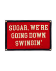The Oxford Pennant "Sugar We're Going Down Swingin' 16x24" is a red rectangular sign with a black border, gold grommets, and cream text. An officially licensed pennant celebrating iconic Fall Out Boy lyrics.