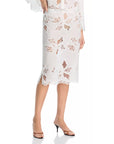A woman’s lower half is shown wearing the Cissa Summer Pencil Skirt—white, knee-length with floral cutout lace and scalloped edges—paired with open-toe heeled sandals.