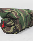 The Hedgehouse Throwbed, a rolled-up military-style sleeping bag with a camouflage pattern and red tassel, reminiscent of outdoor cushions, is shown on a plain white background.
