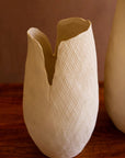 The Bloom Flower Vase S by Kalalou, Inc is a white textured vase with a cracked effect and jagged opening, displayed on a wooden surface against a neutral background.