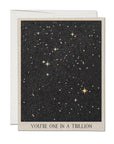 Faire greeting card with a starry night sky design featuring Scottsdale, Arizona landmarks and the phrase "You're one in a trillion" at the bottom, displayed partially open with a visible envelope.
