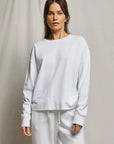 A woman stands against a plain light background, wearing the Perfectwhitetee French Terry Sweatshirt with matching white sweatpants. Her hair is down and her hands are relaxed at her sides.