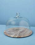 The Be Home 58-377 Waterfall Marble Cloche features a glass dome with a top knob over an empty, round, hand-finished marble base, displayed on a light blue background.