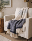 Cream armchair with POM POM Whistler Throw in a softly lit cozy living room, Bungalow Furniture & Accessories.