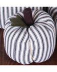 The Faire Pumpkin features black and white vertical stripes, a brown stem, and a green felt leaf, making it a charming autumn ornament for farmhouse decor.