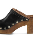 The WOODPECKER clog by Beek features black leather, a wooden sole and heel, brown faux fur lining, and metal studs along the sides.