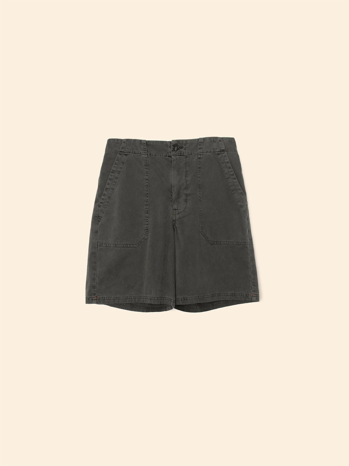 The Toby Short by Xirena is made from vintage washed cotton in dark green, features two large front pockets, and has a tailored fit with a button and zip closure. Proudly made in Los Angeles, these utility shorts have a light beige background.