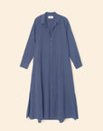 The Xirena Boden Dress, a muted blue cotton poplin shirtdress with long sleeves, collar, side hem slits, and relaxed fit, is shown laid flat on a neutral background.