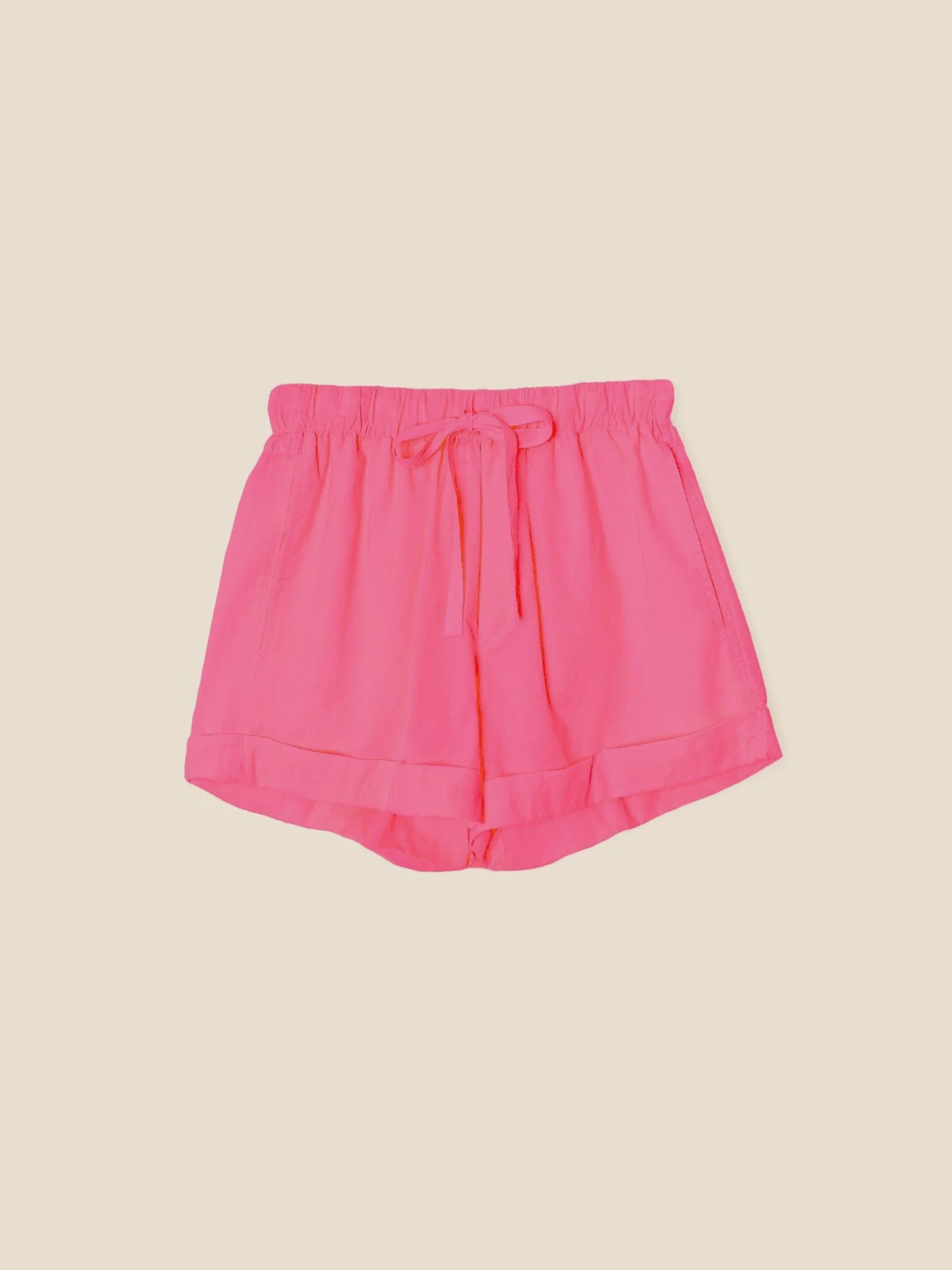 The Declan Short by Xirena is crafted from lightweight cotton poplin in bright pink, featuring an elasticized drawstring waist, rolled cuffs, and side seam pockets, displayed on a plain light beige background.