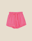 The Declan Short by Xirena is crafted from lightweight cotton poplin in bright pink, featuring an elasticized drawstring waist, rolled cuffs, and side seam pockets, displayed on a plain light beige background.