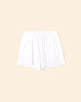 The Shayden Short by Xirena is a white terry sweat short with an elastic waist and side pockets, made from a soft cotton blend and shown flat on a beige background.