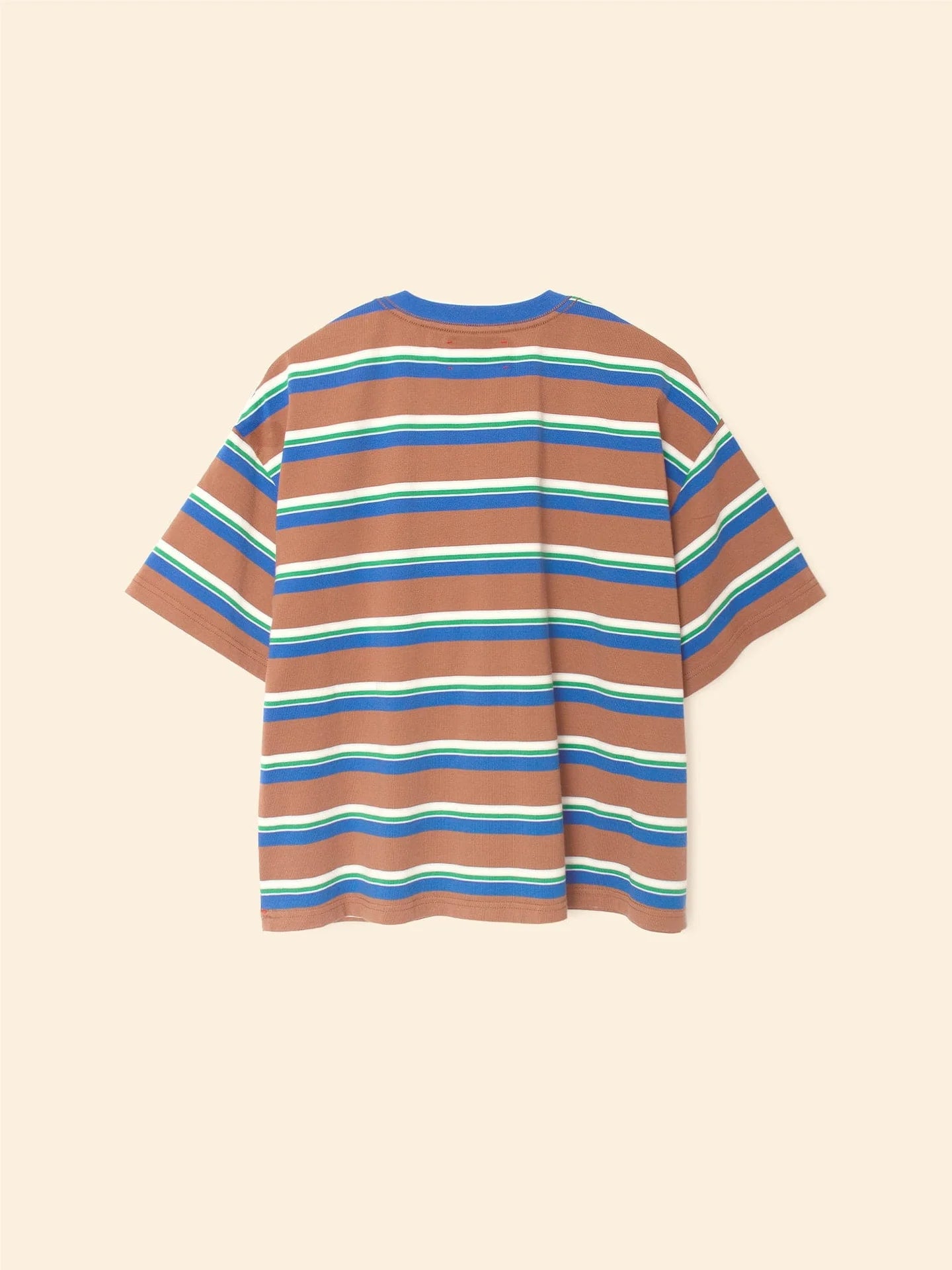 The Paulina Tee by Xirena is a relaxed-fit, short-sleeved striped cotton jersey t-shirt with brown, blue, white, and green horizontal stripes, a contrasting ringer neck, and a left chest pocket. Shown flat on a beige background.