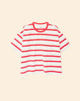 The Xirena Paulina Tee is a short-sleeved striped cotton jersey shirt with a contrast ringer neck, red horizontal stripes, and a small chest pocket, shown against a light beige background.