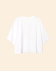 The Roe Top by Xirena is an oversized, short-sleeve T-shirt in plain white, made from a soft cotton blend with a relaxed fit, shown against a beige background.