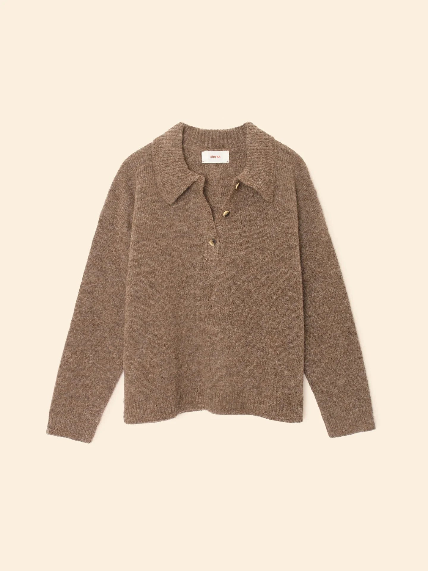 The Ethan Sweater by Xirena is a light brown, long-sleeved baby alpaca Henley pullover with a collar and three buttons at the neckline, shown laid flat on a beige background.