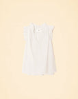 The Bex Top by Xirena is a sleeveless white cotton poplin blouse with ruffle detailing on the shoulders and a flattering V-neckline, shown against a light beige background.