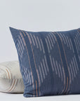 Two Morel Euro Sham Moon. Blue against a plain background; one upright with deep blue and subtle stripe design, and one leaning with a Coyuchi Inc Bungalow-style cream and multicolored curved stripe pattern.