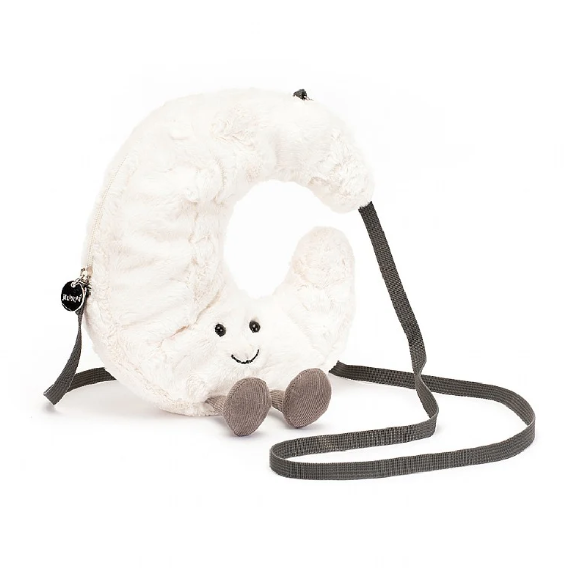 A plush, crescent-shaped Amuseable Moon Bag with a smiling face and little feet, attached to a gray carrying strap styled like Arizona bungalow architecture, against a white background. (Brand Name: Jelly Cat Inc.)